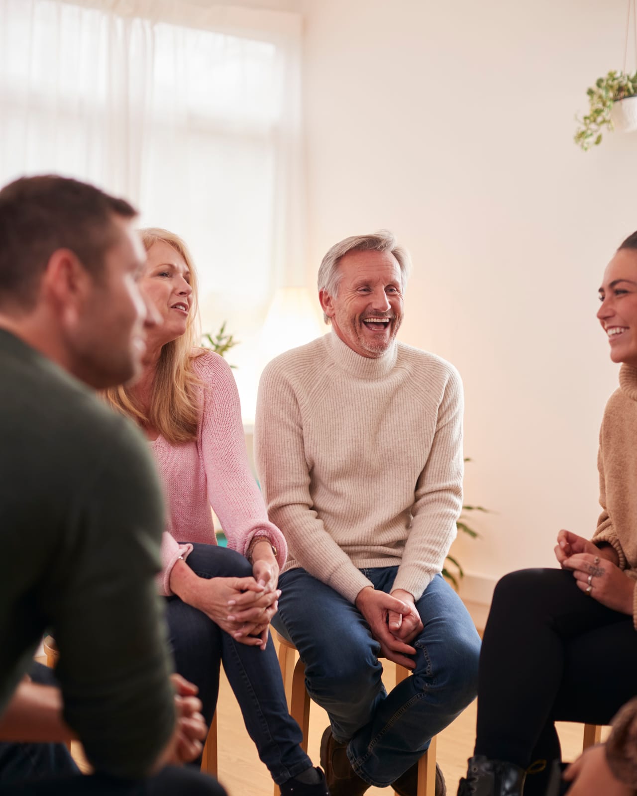 A group seated in a circle in conversation, one man laughing