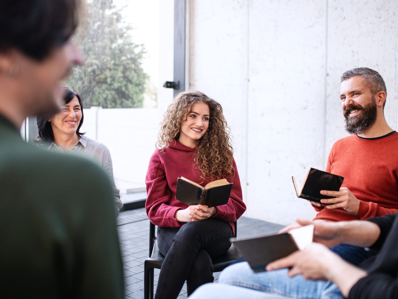 A group seated in a circle with open books, talking and listening